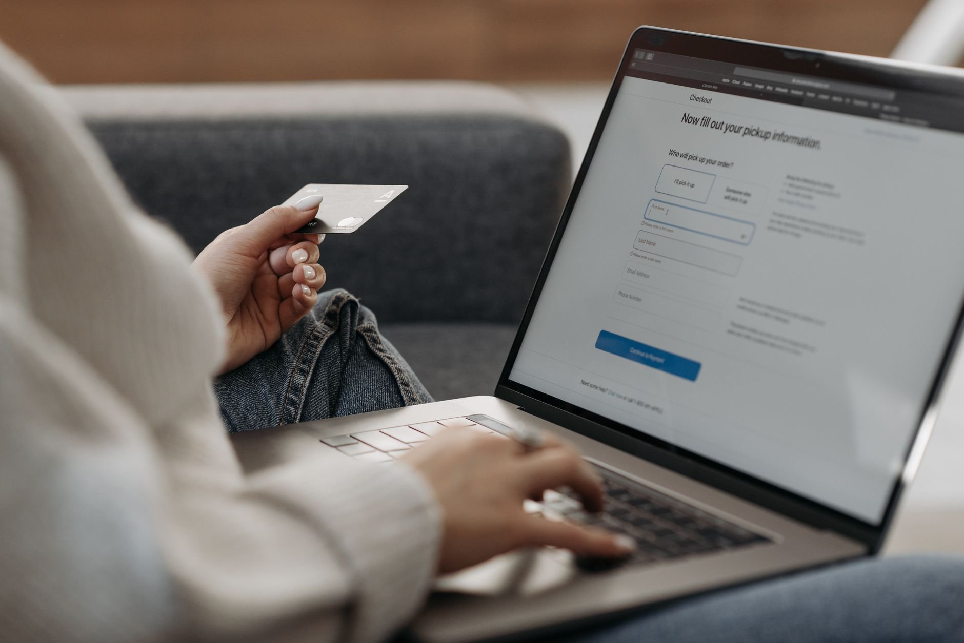 A person shopping online on a laptop with a card in hand