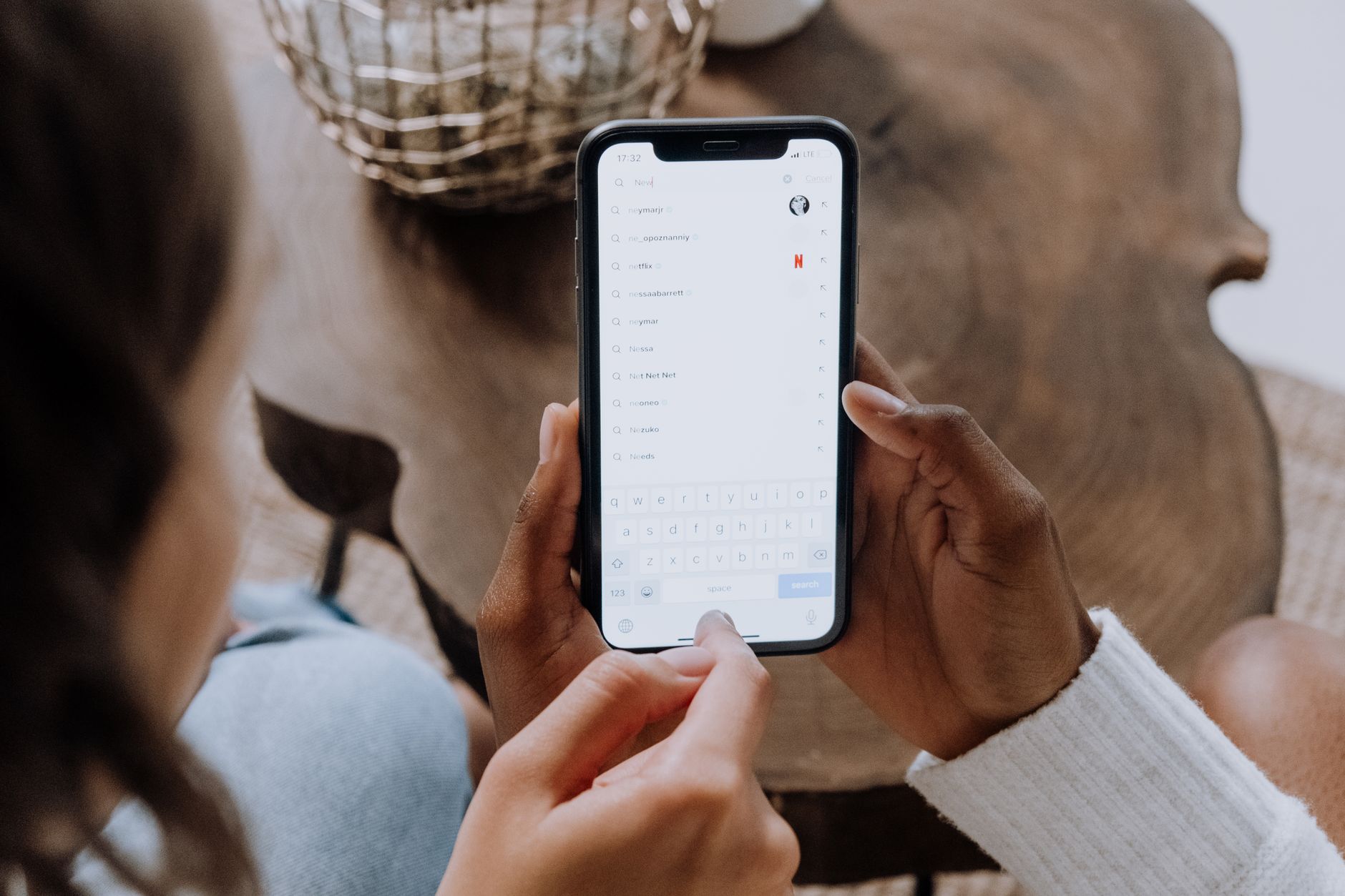 A person holding a phone and typing a search
