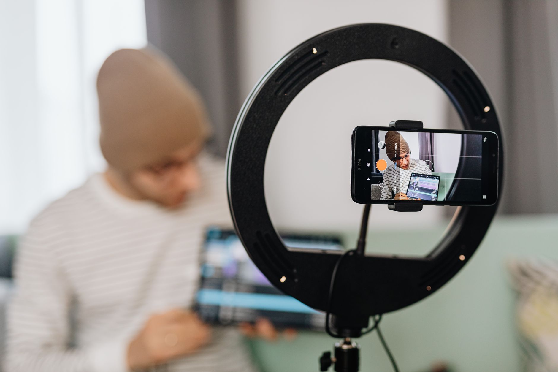 A creator filming with a smartphone mounted in a ring light