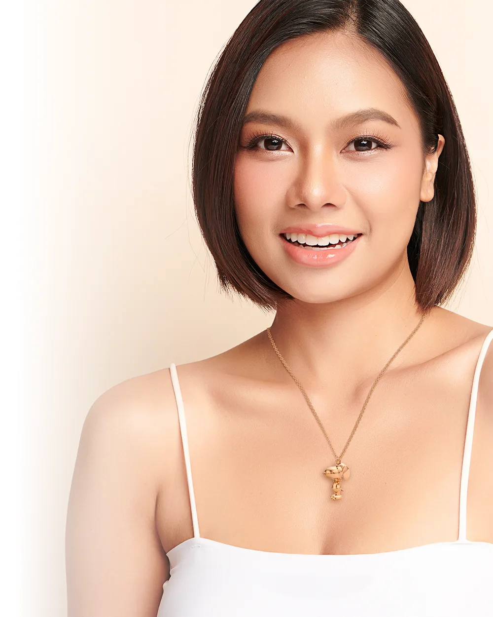 Launch editorial graphic: a model in a white camisole wearing the gold Snoopy pendant